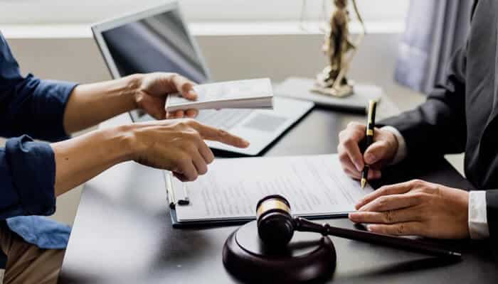 A divorce lawyer reviewing legal documents with a client, with a gavel and law books in the background.