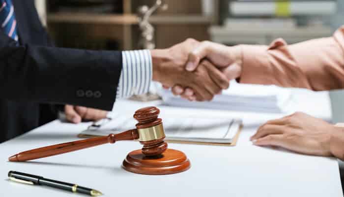 Faster Communication and Easier Access- Myleagalopinion - My Legal Opinion Truck Accident Lawyer meeting a client, shaking hands with legal documents and a gavel on the desk.