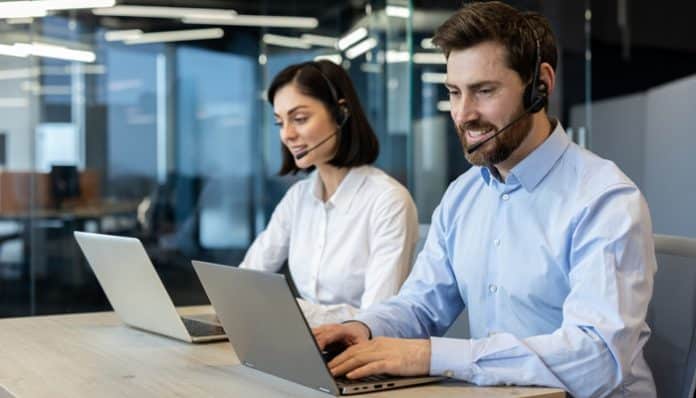 Customer support representatives using laptops and headsets in a modern office, illustrating professional Whistleblower Hotline Services.