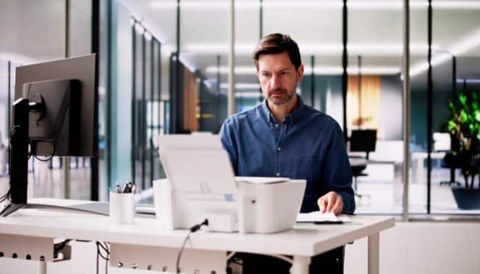Professional using a printer in an office, illustrating the convenience and efficiency of Online Faxing Programs for modern business communication.
