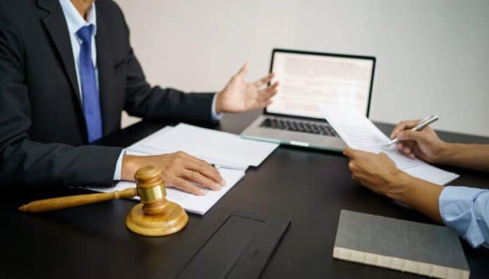 A lawyer discussing VLex court records with a client, with legal documents and a gavel on the desk.