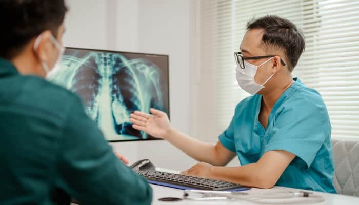 Physician explaining X-ray findings to a patient after a cancer diagnosis, emphasizing why to hire a lawyer after a cancer diagnosis.