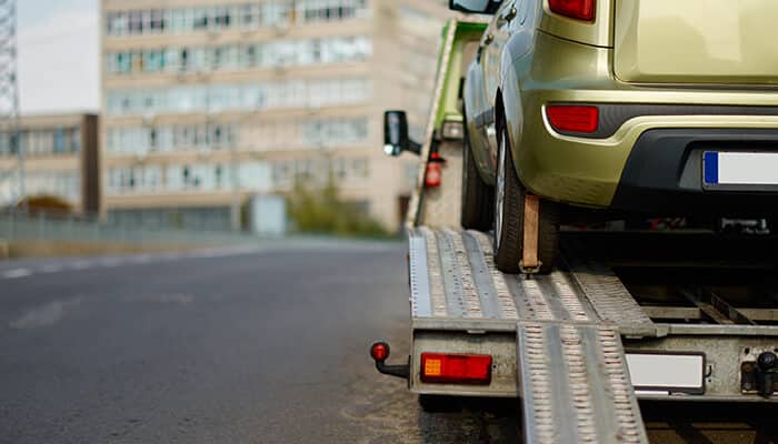 Towing Regulations in Phoenix - Myleagalopinion - My Legal Opinion A car being loaded onto a flatbed trailer on the roadside, illustrating equipment use details relevant to a trailer rental agreement.