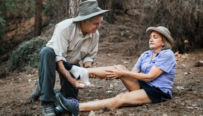 Hiker assisting an injured person outdoors, showing how injuries occur on tribal land during recreational activities.