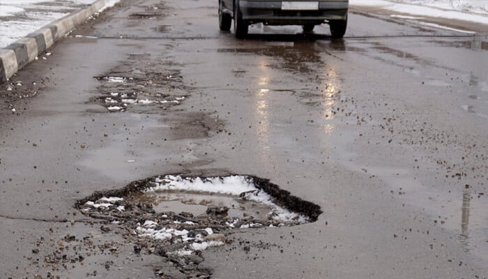 Determining Who Is at Fault - Mylegalopinion - My Legal Opinion Road with visible potholes and snow, highlighting the dangers of poor road maintenance that may result in a pothole injury claim.