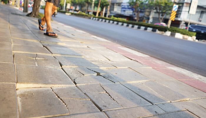 Failure to Maintain Safe Walkways - Mylegalopinion - My Legal Opinion Uneven sidewalk near parked vehicles showing trip hazards commonly faced when parking under the eaves and walking to a car.