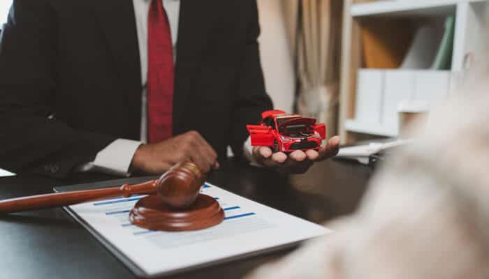 How Do You Ensure You Receive Fair Compensation - Mylegalopinion - My Legal Opinion Attorney discussing a motorcycle accident in Virginia Beach case with a client, holding a toy model car and a gavel.