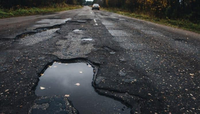 Damaged road with large potholes, illustrating a potential hazard that could lead to a pothole injury claim.