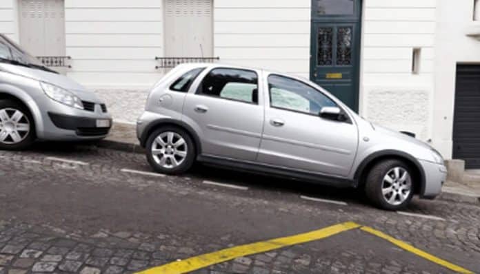 Car parked beneath building eaves on a sloped surface, highlighting potential hazards associated with parking under the eaves.
