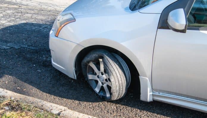 Car with a blown tire blows after a high-speed blowout at 70 MPH, showing the damage caused by the tire blowout on the side of the road.