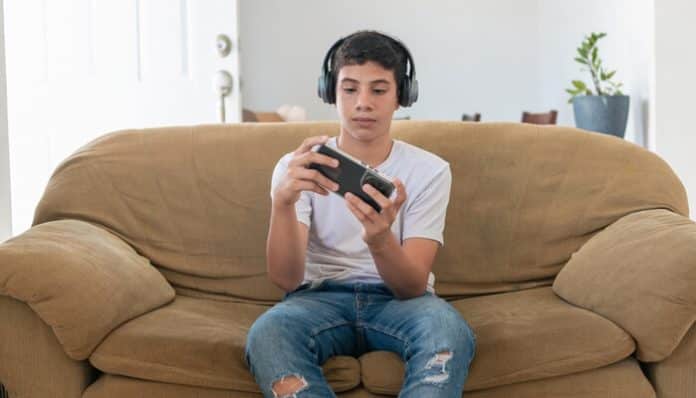 Teenager playing video games on a couch, highlighting concerns related to video game addiction lawsuit.