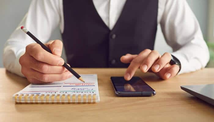 Professional documenting work tasks and checking a phone, highlighting the potential for repetitive stress injuries in the workplace.