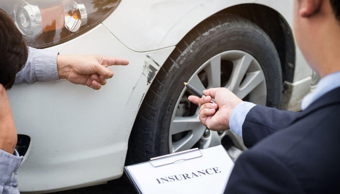 The Way Insurance Companies Apply Shared Fault - My Legal Opinion - My Legal Opinion Fault in a Car Accident: Insurance adjuster pointing out damage to a vehicle while discussing liability and claims with the driver, focusing on fault determination.