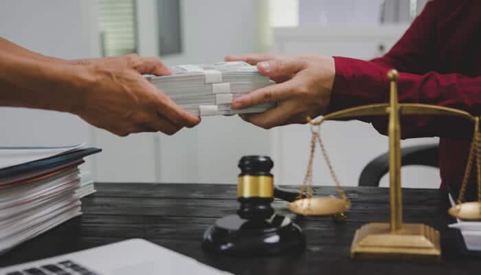 Understanding Contingency Fee Agreements - My Legal Opinion - My Legal Opinion Hands exchanging legal documents across a desk with a gavel and scales of justice, symbolizing services provided by a Personal Injury Lawyer in Toronto, Ontario, Canada.