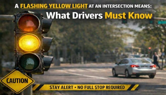 A Flashing Yellow Light at an Intersection means: Stay alert, no full stop required. Caution sign with flashing yellow traffic light at a busy intersection.