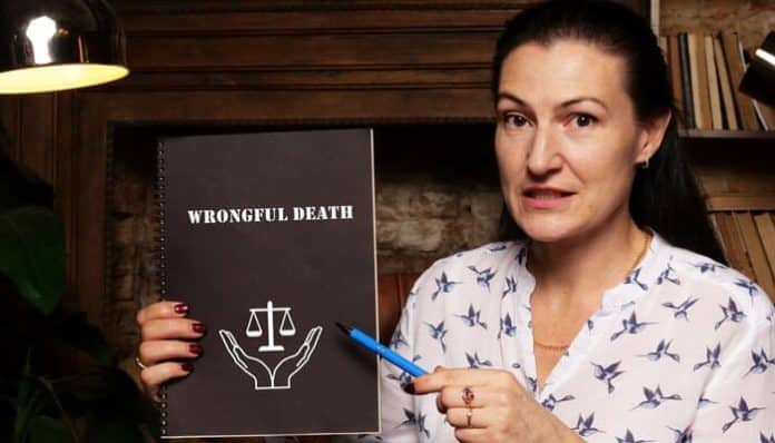 Woman holding a brochure titled 'Wrongful Death,' explaining legal aspects of wrongful death claims with a focused expression, using a pen to highlight details.