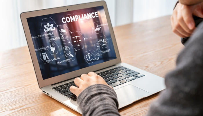 Integrating Quality and Compliance into Product Development - My Legal Opinion - My Legal Opinion A person using a laptop with a compliance dashboard displaying key standards, regulations, and quality assurance – essential for biotech and pharmaceutical innovation.