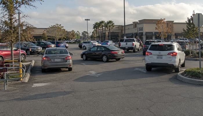 Confusing Traffic Flow Patterns - My Legal Opinion - My Legal Opinion Parking lot in front of a shopping center with several cars parked and driving; palm trees in the background.