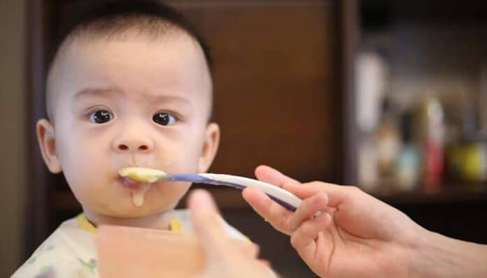 Baby Food Contains Dangerous Toxins concerns shown through an infant being fed baby food, highlighting potential risks of harmful contaminants, heavy metals, and food safety issues affecting young children.