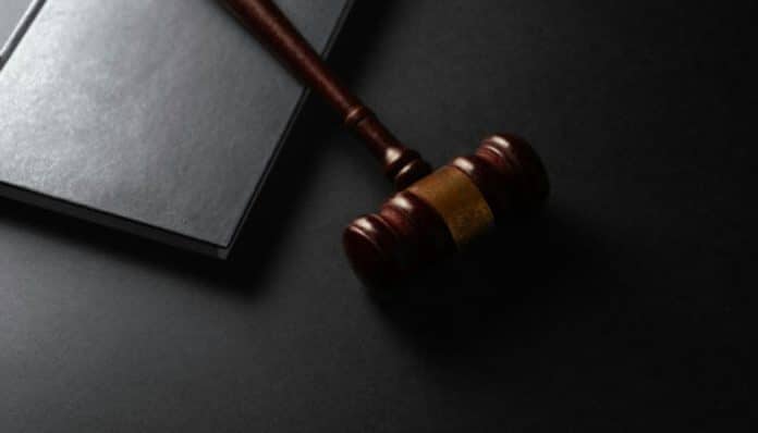 Judge's wooden gavel rests on a dark surface beside a closed black legal book